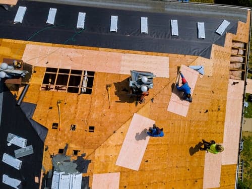 Aerial view of a Florida Sky Roofing crew replacing a roof, decking exposed and underlayment going down